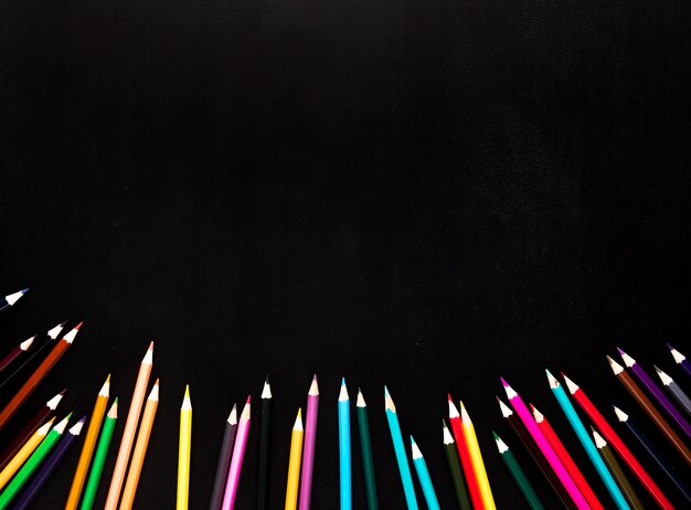 Scattered sharpened color pencils placed in bottom of black background