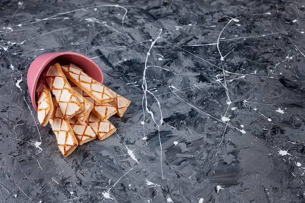 Scattered waffle cookies in a pink bucket .