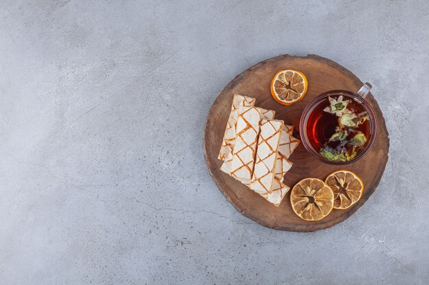 Scattered waffle cookies with a cup of herbal tea . 