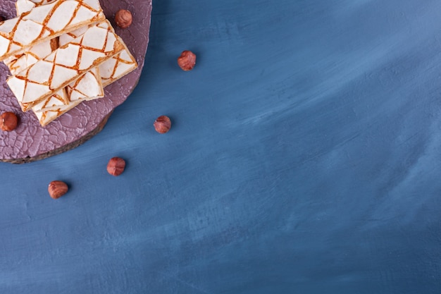 Free photo scattered waffle cookies with hazelnuts placed on blue .