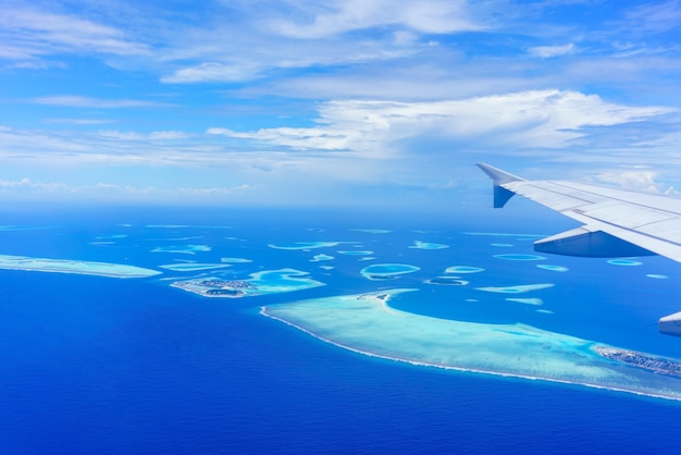 Пейзаж из окна самолета видя крыло самолета белые облака голубое небо мальдивские острова
