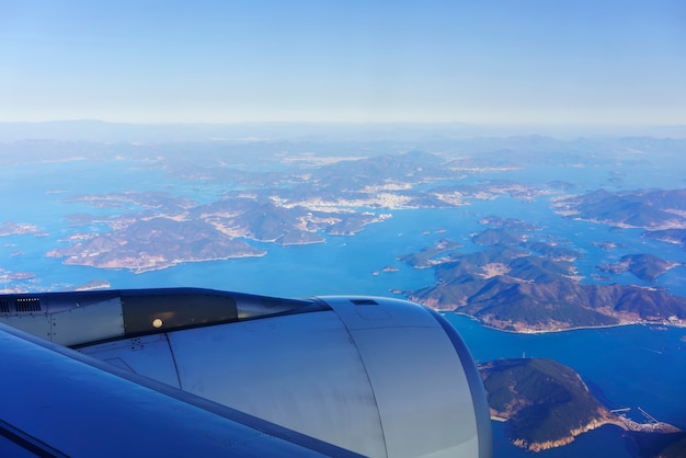 Пейзаж из окна самолета с видом на голубое небо и южно-корейский полуостров и прилегающие к нему острова утром