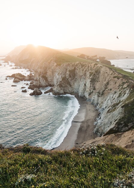 Scenery of ocean waves moving towards the rock formation during sunrise