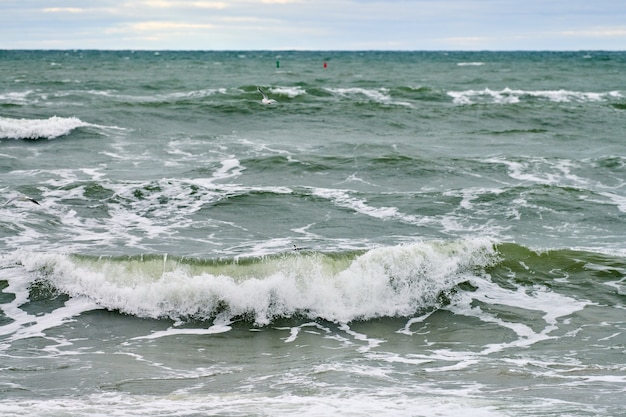 Живописный вид на синее море с бурлящими и пенящимися волнами и красивым облачным небом