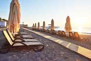 Бесплатное фото Живописный вид на частный песчаный пляж с шезлонгами и парасоками на море и горы. курорт.