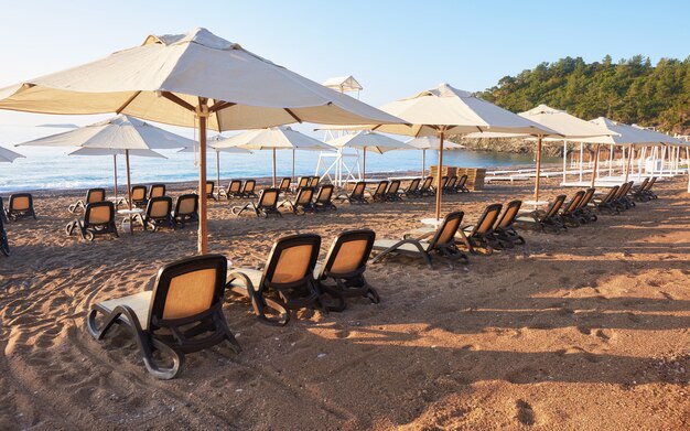 Scenic view of private sandy beach with sun beds from the sea and the mountains. Amara Dols Vita Luxury Hotel. Resort. Tekirova Kemer. Turkey.