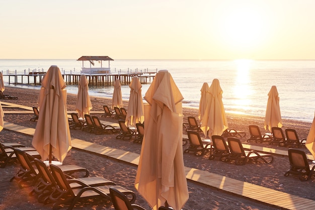 Foto gratuita vista panoramica della spiaggia sabbiosa privata con lettini e ombrelloni sul mare e sulle montagne. ricorrere.