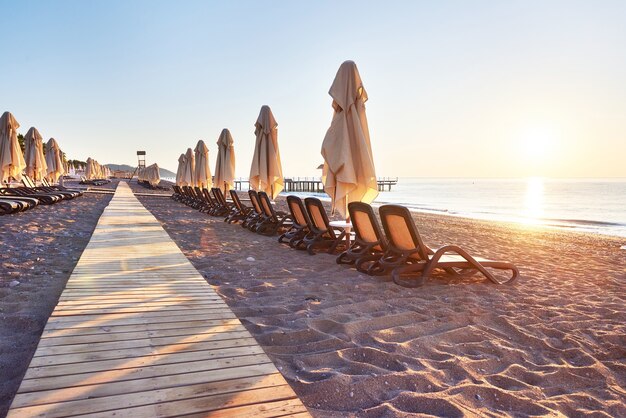 Scenic view of private sandy beach with sun beds and parasokamy the sea and mountains. Resort.