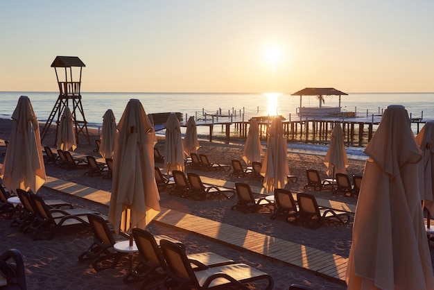 Scenic view of private sandy beach with sun beds and parasokamy the sea and mountains. Resort.