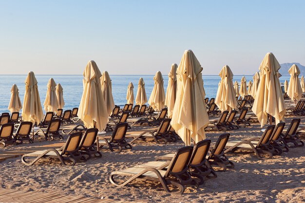 Scenic view of private sandy beach with sun beds and parasokamy the sea and mountains. Resort.