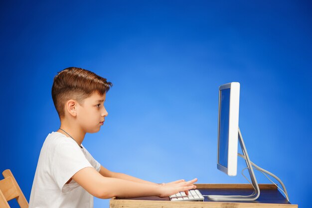 School-age boy sitting in front of the monitor laptop