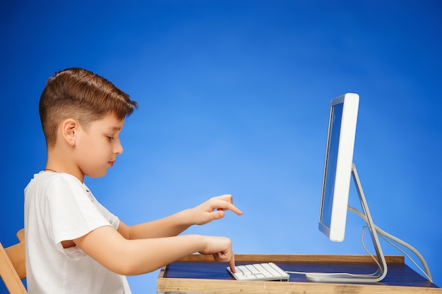 Мальчик школьного возраста сидит перед монитором ноутбука