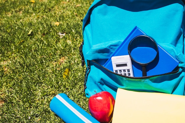 School backpack with school supplies on grass