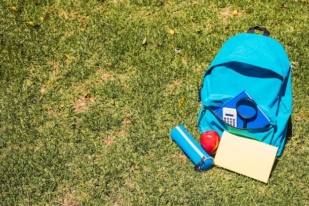 文房具の芝生の上で学校のバックパック