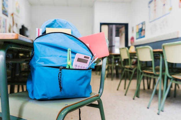 School backpack with supplies on chair