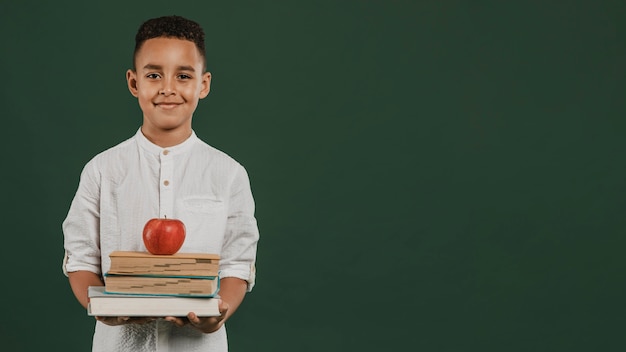 School boy holding books and apple