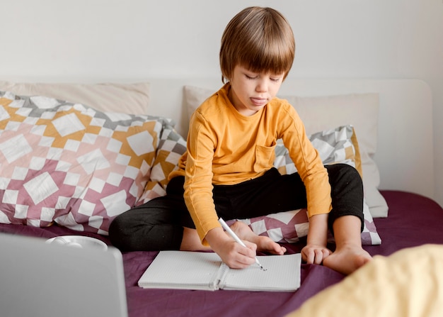 School boy sitting in bed virtual classes