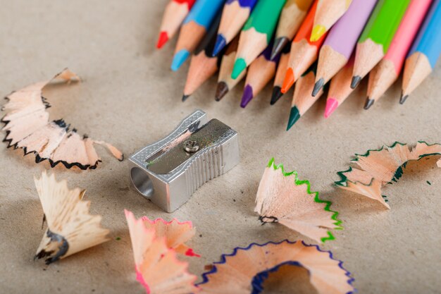 School and equipment concept with pencils, sharpener, shavings on paper high.