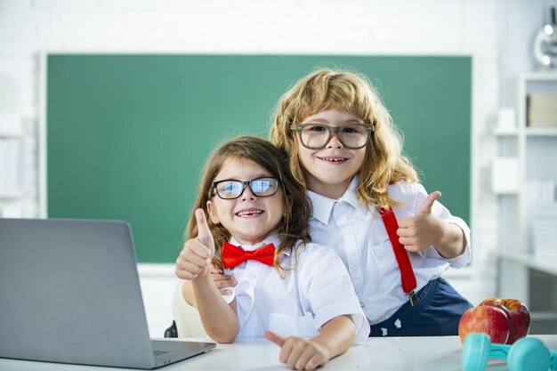 학교 친구 두 명의 학교 아이들이 칠판 근처 학교에서 엄지손가락을 들고 있는 귀여운 소녀와 소년