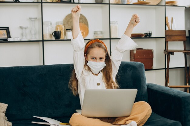 School girl studying at home wearing mask, distant learning
