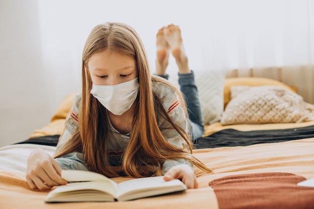 School girl studying at home wearing mask, distant learning