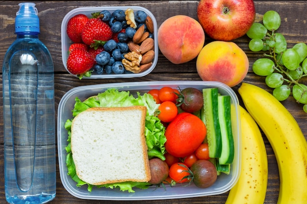 Школьные ланч-боксы с бутербродом, свежими фруктами и овощами
