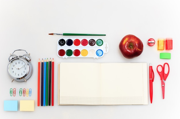 School set with notebooks, pencils, brush, scissors and apple on white