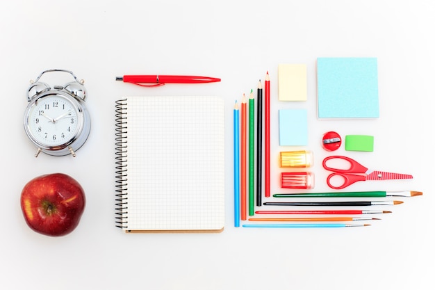 School set with notebooks, pencils, brush, scissors and apple on white