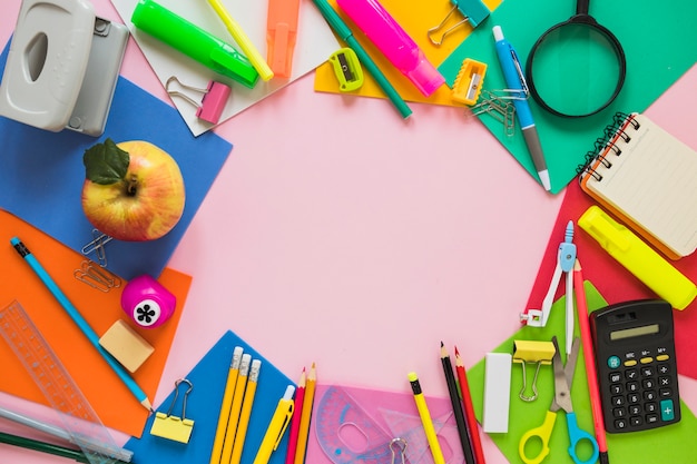 School supplies and apple laid in circle