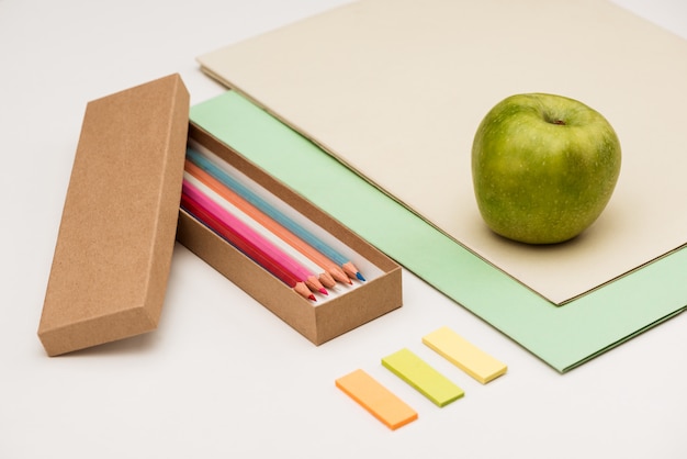 School supplies and apple on white table