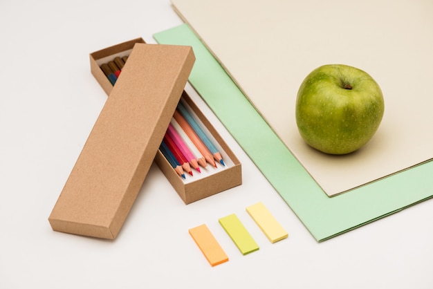 School supplies and apple on white table