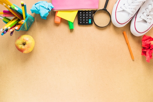 Foto gratuita materiale scolastico vicino a mele e scarpe da ginnastica