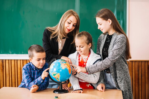 School teacher and students working with globe