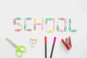 Free photo school word made up of colorful paper clips near stationeries on white background