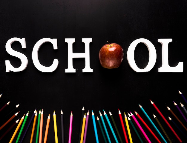Free photo school word and strewn color pencils on black background