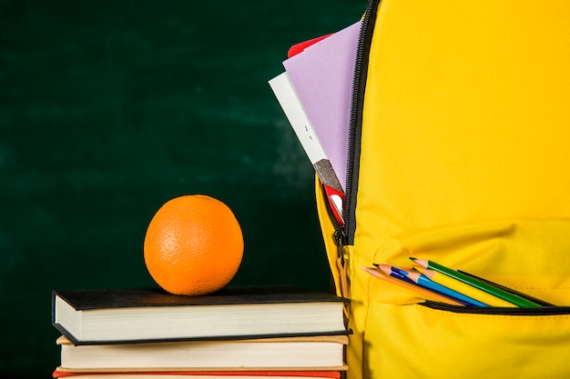 Schoolbag, pile of books and orange