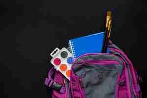 Free photo schoolbag with brushes, watercolors and copybook