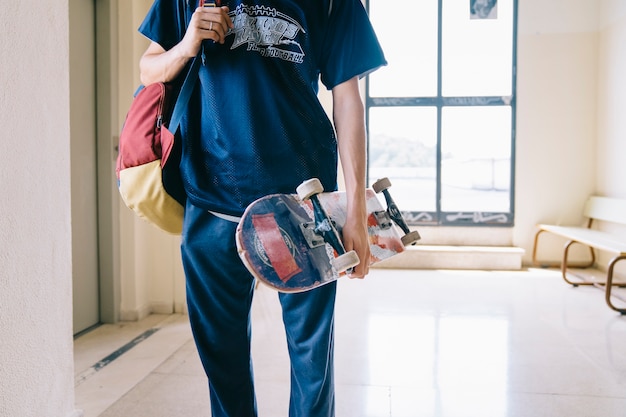 Schoolboy carrying skateboard