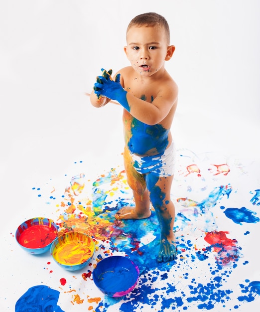 Schoolboy playing with pots full of paint