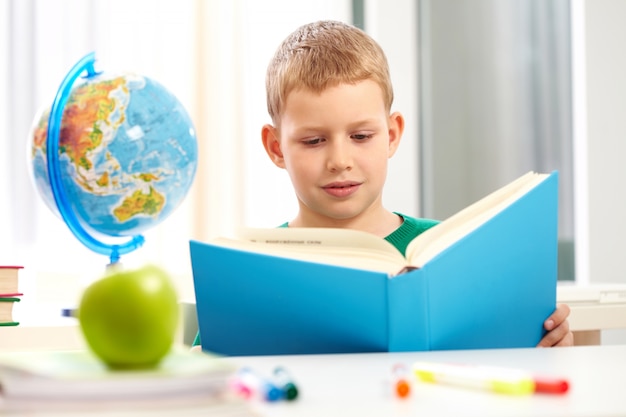 Schoolboy reading a heavy blue book