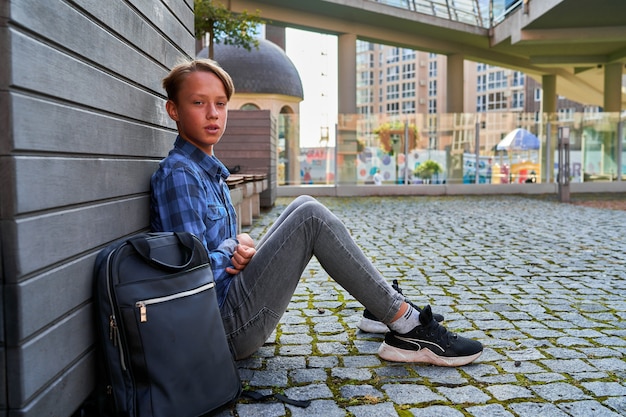 Free photo schoolboy with a backpack on the street after school.