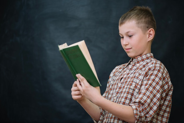 Free photo schoolboy with book reading smiling