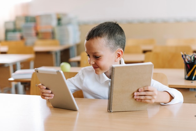 Schoolboy with notepad and tablet