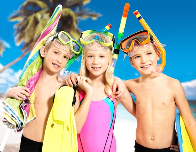 Schoolchild kids standing together in bright color swimwear with swimming mask on head .