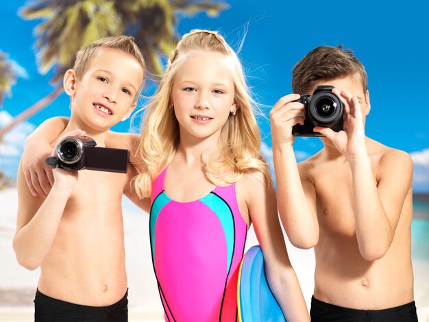 Schoolchild kids standing with photo and video camera in hands.