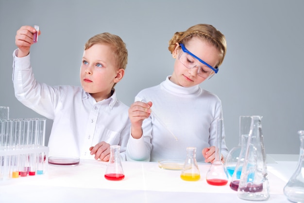 Schoolchildren analyzing test tubes with liquids