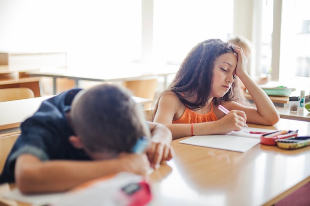 Free photo schoolchildren leaning on table sleeping