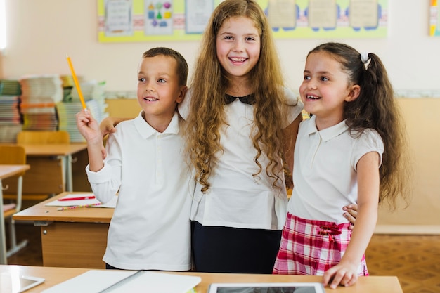 Schoolchildren standing in classroom hugging