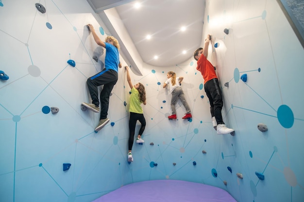 Schoolchildren in training hanging on climbing wall