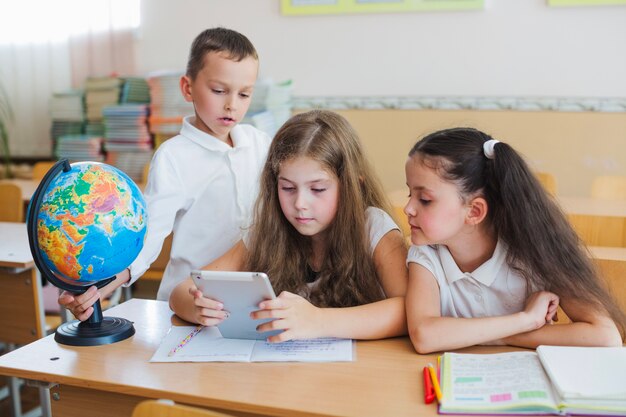 Schoolchildren watching tablet with interest